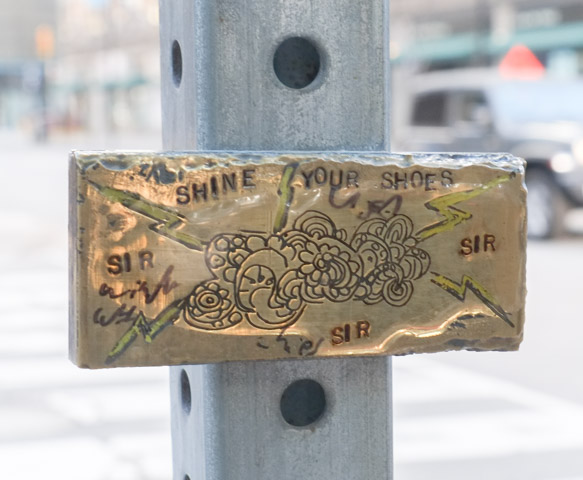 small brass plaque on a post, words engraved into it