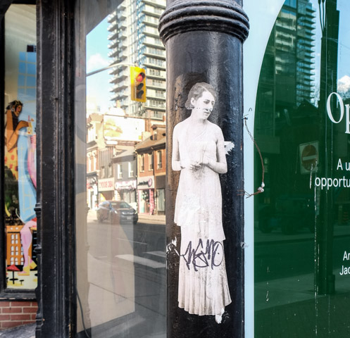 33wallflower33 pasteup graffiti on the corner of a building, woman in long dress