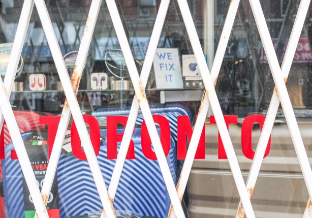 folding metal grate over shop window, word toronto in red is written on the window