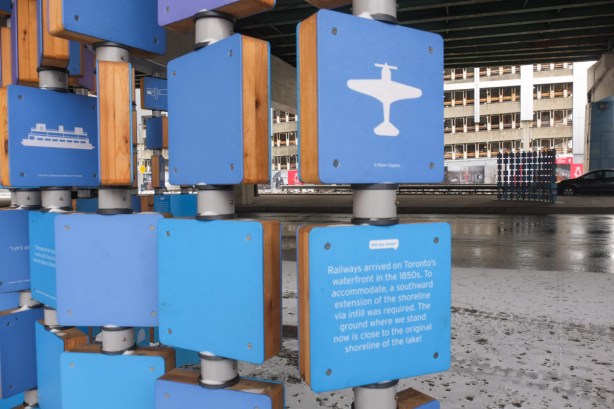 blue squares arranged in a grid as part of a public art installation. some squares have simple white pictures and some squares have words written in white