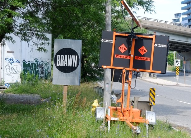 sign saying brawn on a wood stake in the grass beside Eastern Ave