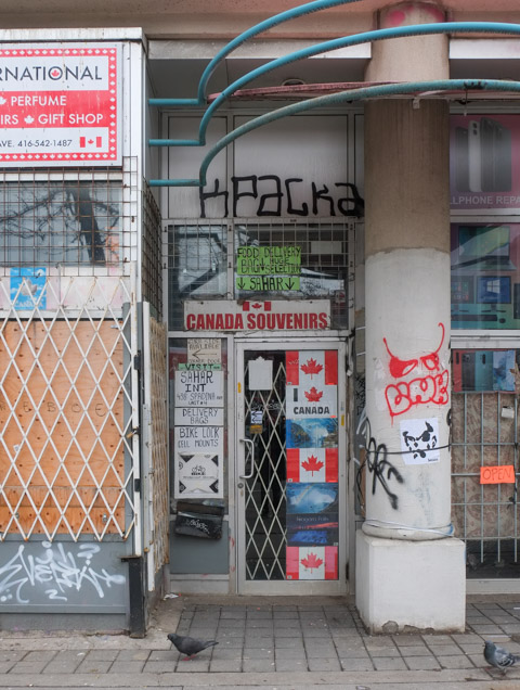 store front on spadina, closed, with canada flags on door,