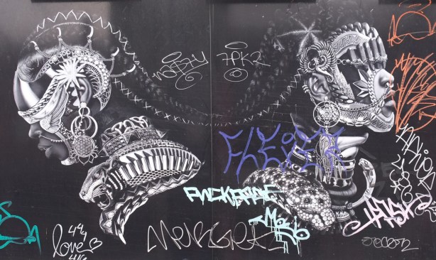 black and white street art by Adeyemi Adegbesan of two Black males with elaborate jewellery and chains joining them, also a collar that looks like a metal jaguar or tiger roaring,