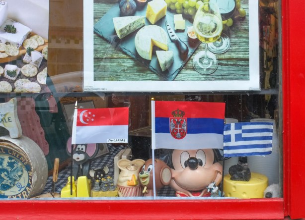 items in a cheese store window, toy mice, mickey mouse, flags of Greece, Serbia, and Singapore