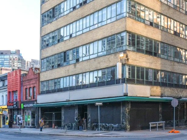 old church of scientology building on yonge street, boarded up a street level, cracked glass windows, 
