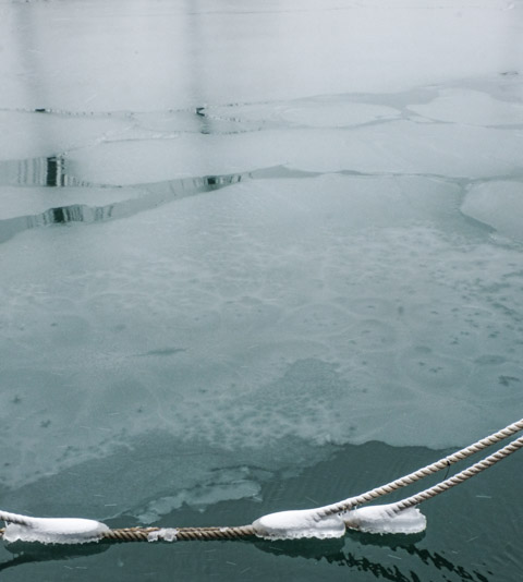 ice and reflections on the water, with ropes from a boat with snow and ice on them