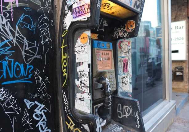 old open style phone booth on yonge street, covered with graffiti