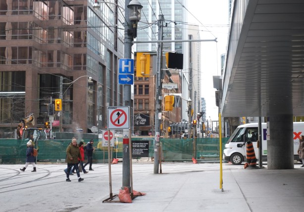 Queen Street East at Victoria. Street to the west towards Yonge street is closed, green and metal fence blocking traffic and pedestrians, construction site for new Ontario Line subway 