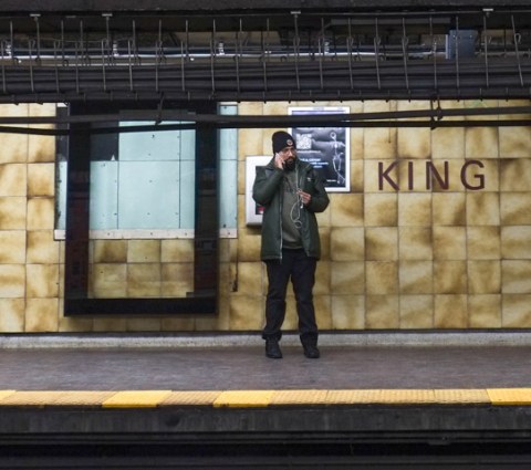 a man stands on the platform at king subay station, talking on his phone