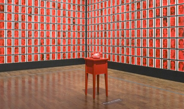 an art piece of pictures on two sides of a corner, and a red phone in the middle Hey Hey Paula by Sarindar Dhaliwal