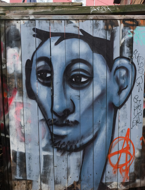 portrait of a blue man with a mustache by Philip saunders, on a wood fence