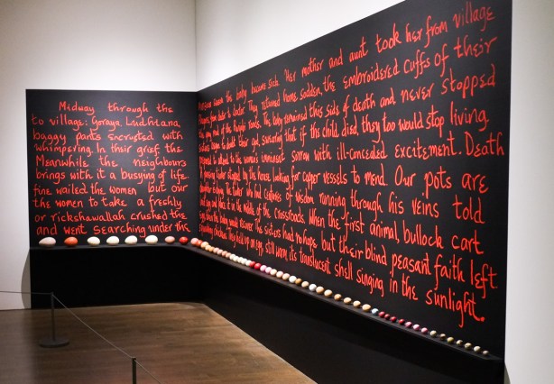 a story written in red letters on a black wall, goes around a corner