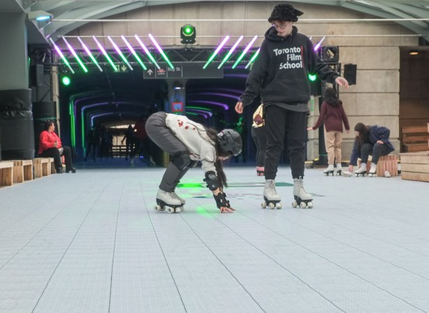 two women roller skating, one has fallen and the other is helping her up