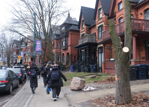 people walking on the sidewalk, walking past large old brick houses