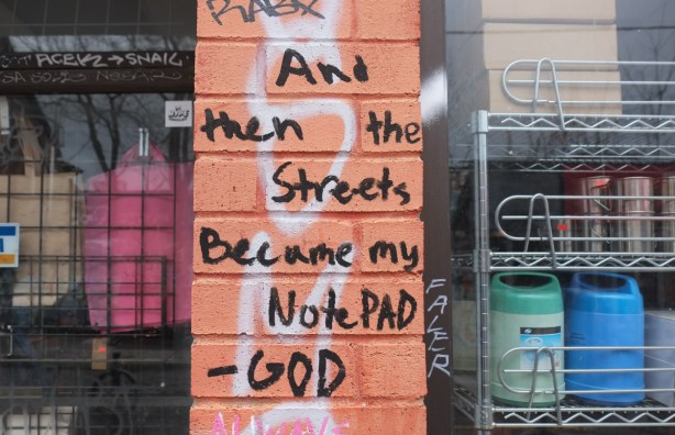 written in large black letters on a pinkish salmon coloured brick wall, and then the streets became my notepad, god