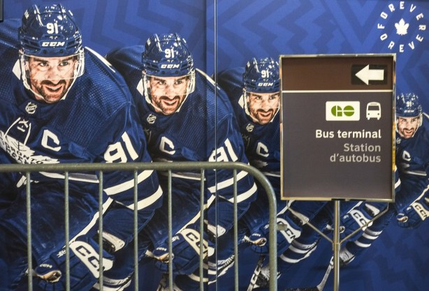 Picture of Maple Leafs captain John Tavares in quadruplicate, in uniform and helmet, photo on the wall behind a sign giving directions to the new GO bus station 