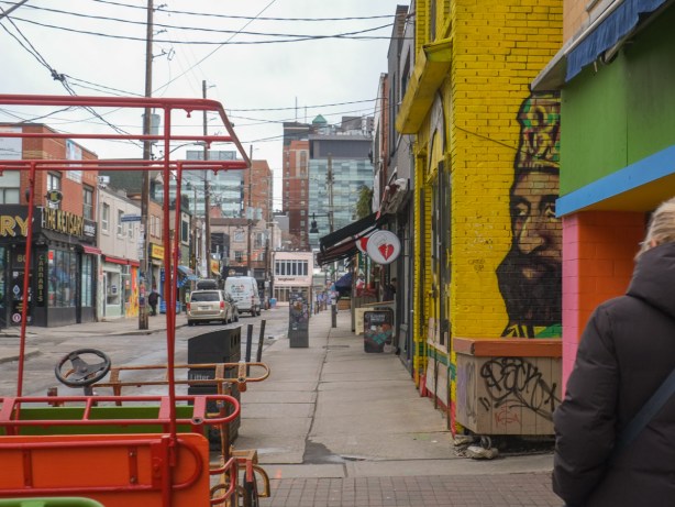 looking west on Baldwin, yellow wall with painting of man with crown on head, on the side of one of the buildings