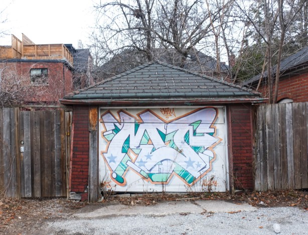garage in alley, white door with street art on it 