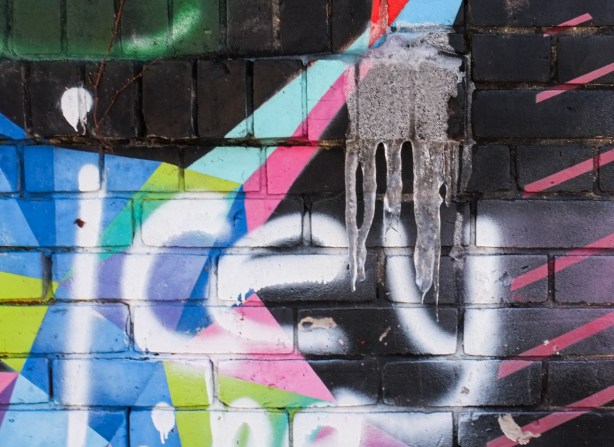 graffiti on wall, white on black, text that says icey, above it are 3 icicles