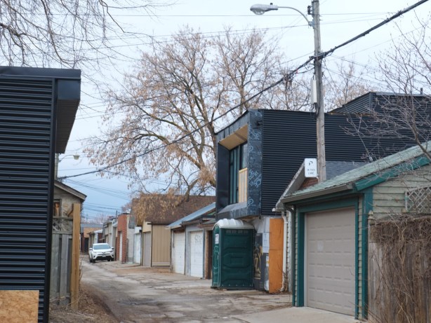 black clad two storey house, dwelling with a large window facing the alley on the upper floor, infill in an alley 