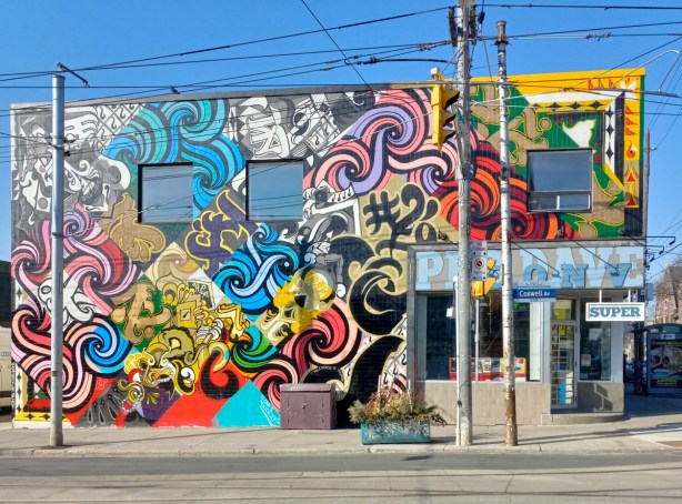 mural covering the side of the convenience store building on the southwest corner of coxwell and gerrard, many elements in the mural, mostly abstracr shapes and colours