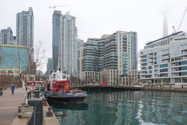 toronto waterfront at spadina quay, omni coastal tug boat is docked, condos on the waterfront, CN tower obscured by fog, grey cloudy day