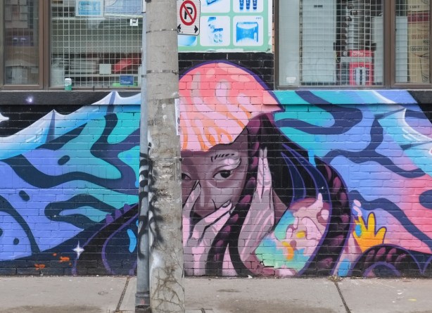 part of mural with tigers and women face, under window on chinatown store