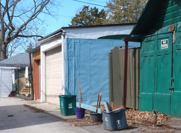 garages in alley, dark green garage door, bright blue wall,