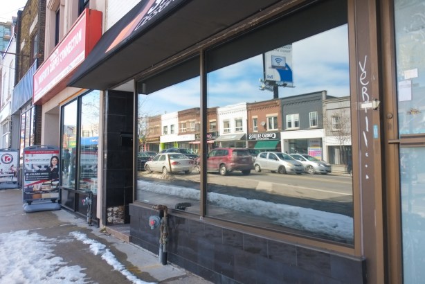 reflections in a window of a store on Danforth, cars and stores across the street can be seen. 