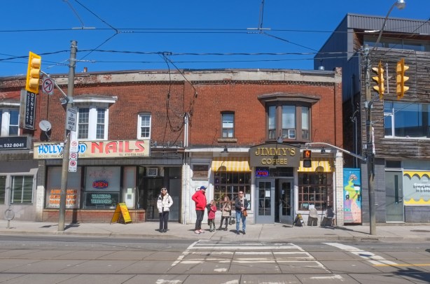 looking across Dundas West towards Jimmys Coffee, people waiting to cross with traffic light