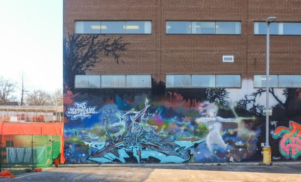 street art on the back of a brick building, parking lot in front