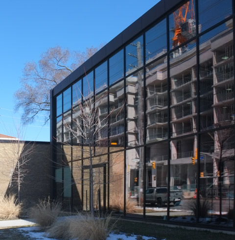 condo construction with red crane reflected in a large window in a building across the street from it
