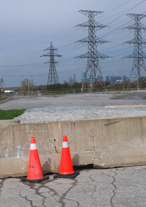 two small orange cones in front of a concrete barrier, large metal hydro poles in the background