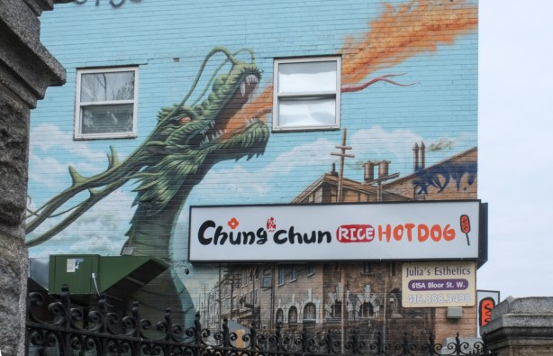 outside wall of chung chun rice hot dog restaurant, a mural with a large green fire breathing dragon