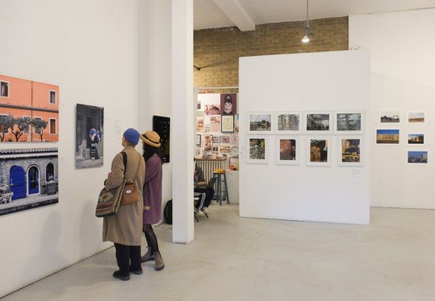 two women in an art gallery looking at photographs that are mounted on the wall