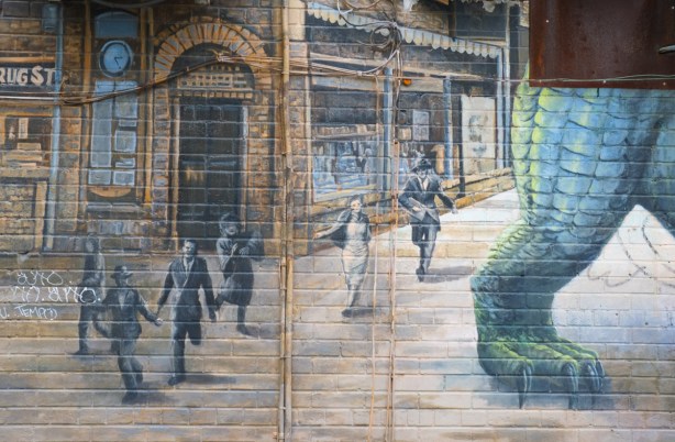 part of a larger mural, people running outside shops on sidewalk, running away from green monster