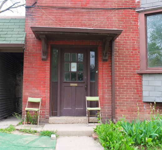 chairs, one on either side of a brown door, red brick building