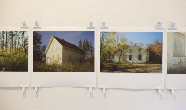 photographs of rural abandoned buildings by Lilianne Schneider, on a gallery wall