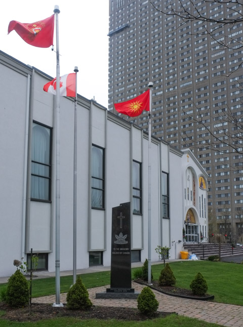 United Macedonian unknown soldier memorial outside greek orthodox church, along with Canadian and macedonian flags