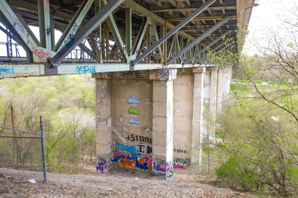 graffiti on lower parts of concrete pillars hoding up the Millwood bridge beside the Don River, spring greenery