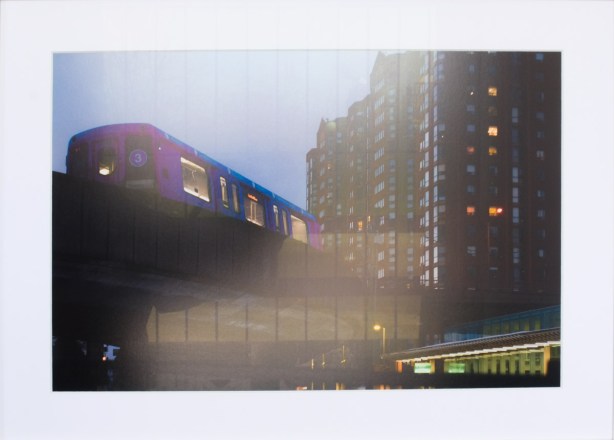 framed photo of Scarborough RT through a window, with reflections of interior lights, passing a large building, framed photo on gallery wall