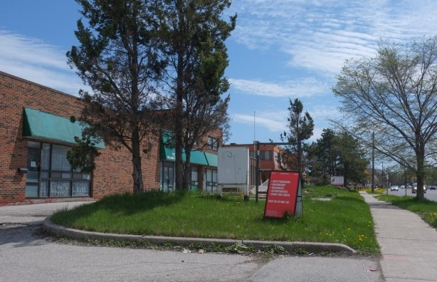 low rise light industrial building on Bellamy, with red sign in front for Arts group