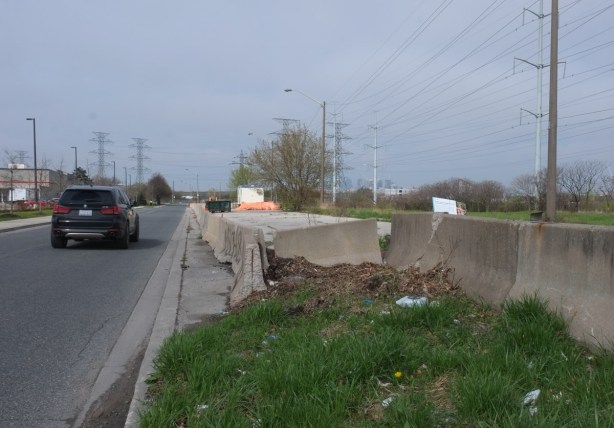 car driving on street behind costco, vacant land and hydro right of way on the other side of street
