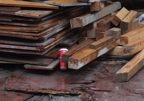 tims coffee cup wedge into the bottom of a pile of lumber, between sheets of plywood and the stack of 4 by 4s