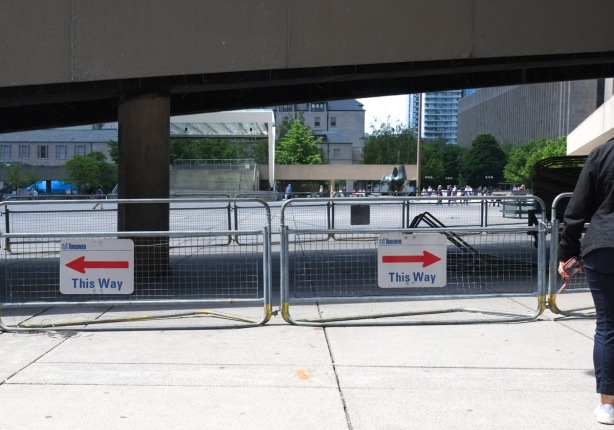 barricades under a ramp with two signs saying this way, with red arrows, pointing opposite directions from each other