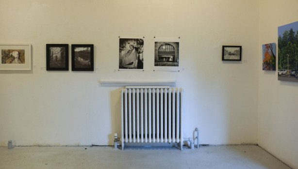 photographs on display in a gallery, on a wall with a white radiator