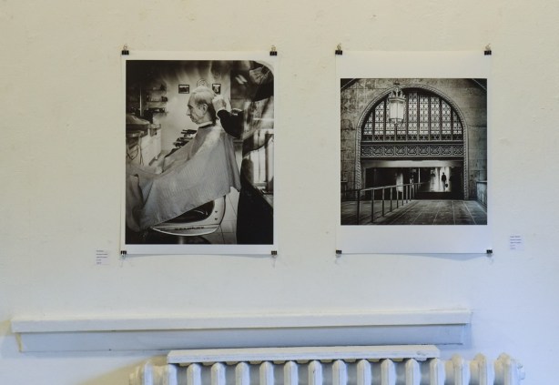 two black and white photos on the wall of gallery 1313, above a radiator