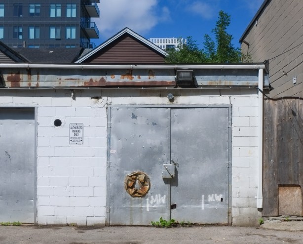 garage in alley, white concrete block with grey metal door