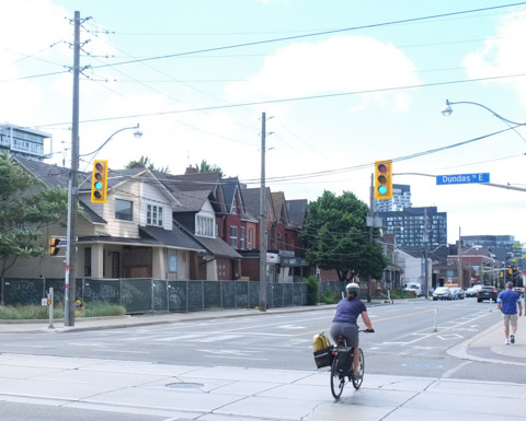 cyclist on bike, traveling south on river at dundas, row of houses in the background