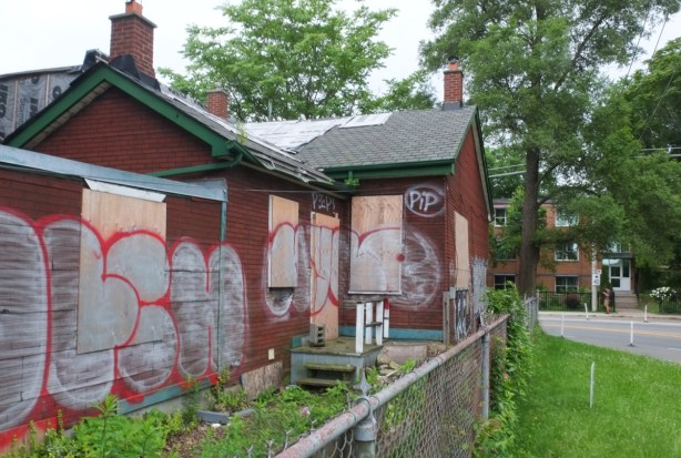 graffiti tags on plywood used to board up windows and doors on empty old houses